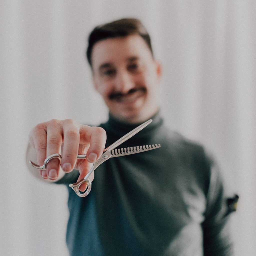 Hairdesigner Ray aus Zürich mit einer Effilierschere in der Hand.